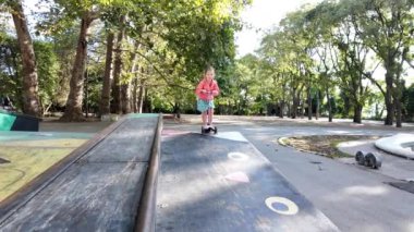 Mutlu kız dışarıda motosikletiyle eğleniyor. Parkta scooter süren bir kız.. 