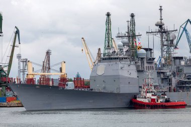 Römorkör limana yanaşmak için askeri gemiyi destekliyor.