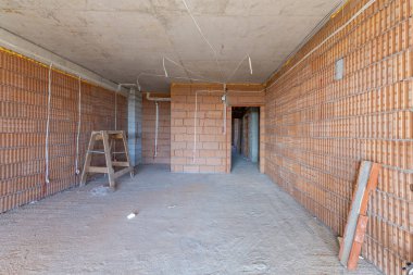 İnşaat halindeki binanın içinde bitmemiş bir oda. Tuğla kırmızı duvarlar. Yeni ev.