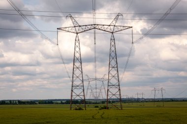 Elektrik direkleri ve kablo hatları bulutlu gökyüzüne karşı 