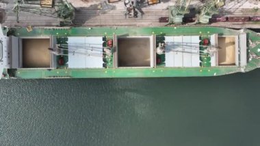 Limandaki vinçlerle kuru buğday kargo gemisi yükleniyor. Deniz kargo gemisinin ambarına hava görüntüsü yükleniyor