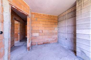 İnşaat halindeki binanın içinde bitmemiş bir oda. Tuğla kırmızı duvarlar. Yeni ev.