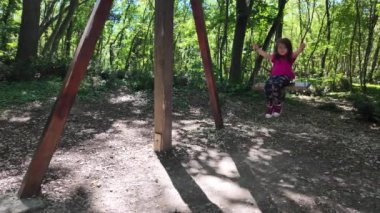 Küçük mutlu kız parkta eğleniyor. Sallanıyor salıncakta. 