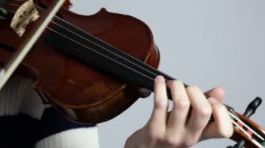 Kız keman çalıyor. Keman çalan ellerin yakın çekimi. Kadın, keman müzisyeni, çalıyor.