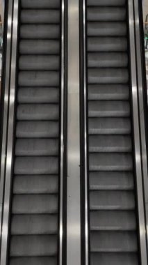 Alışveriş merkezinde boş merdivenlerin yukarı aşağı koşuşunun dikey görüntüsü. Modern yürüyen merdiven.