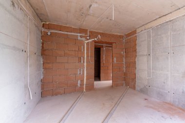 İnşaat halindeki binanın içinde bitmemiş bir oda. Tuğla kırmızı duvarlar. Yeni ev.