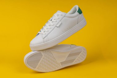 Çift sarı arka plan üzerinde yeni beyaz spor ayakkabı