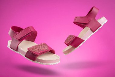 Pembe arka planda iki pembe sandalet. Kızlar için sevimli pembe sandaletler..