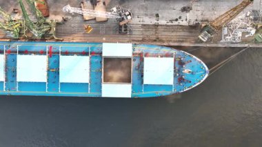 Limandaki vinçlerle kuru buğday kargo gemisi yükleniyor. Deniz kargo gemisinin ambarına hava görüntüsü yükleniyor