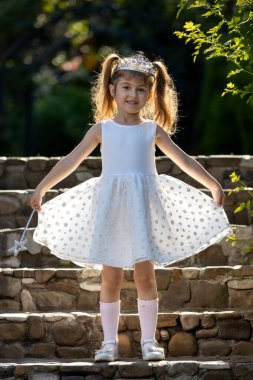 Kafasında taç olan beyaz elbiseli küçük prenses. Taçlı ve beyaz elbiseli genç kız.