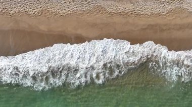 Okyanus dalgalarının kumlu bir sahile çarptığı hava manzarası. Doğal doku, yaz titreşimleri ve manzaralı kıyı güzelliği..