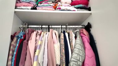 Renkli kız kıyafetleriyle dolu açık çocuk dolabının videosu.