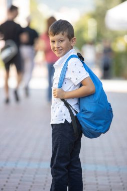 Okul çantalı, okul bahçesinde sırt çantalı mutlu bir okul çocuğu. Okula gidiyorum. Okula geri dön.