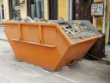 Orange Endüstriyel Çöp Konteynırı Şehir Caddesi 'nde enkaz ve yıkıntı dolu. Bina Yenileme Atık Yönetimi ve Temizleme Konsepti