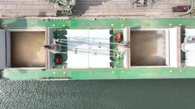 Limandaki vinçlerle kuru buğday kargo gemisi yükleniyor. Deniz kargo gemisinin ambarına hava görüntüsü yükleniyor
