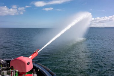 Firefighting Water Cannon Spraying Over Open Sea from Vessel. Maritime Safety, Emergency Response, and Marine Equipment Demonstration