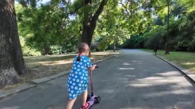 Parkta scooter kullanan tatlı küçük kız.
