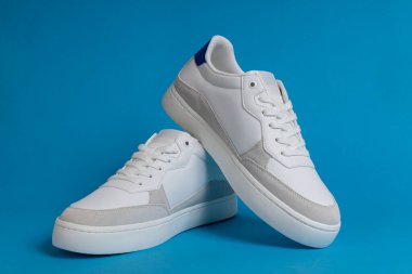 Mavi Arkaplanda şık beyaz deri ve süet spor ayakkabılar. Moda Sıradan Spor Ayakkabıları