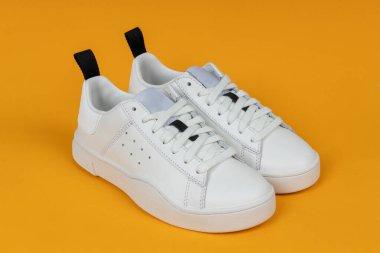 Sarı arka planda bir çift yeni beyaz spor ayakkabı. Kadın spor ayakkabıları..