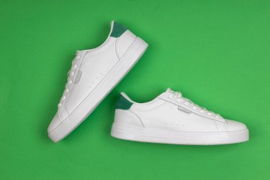 Yeşil arka planda bir çift yeni beyaz spor ayakkabı