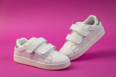 Pembe arka planda cırt cırt cırtlı şık beyaz çocuk ayakkabıları. Aktif oyun için çocuk ayakkabıları ve okul konseptine geri dönüş.