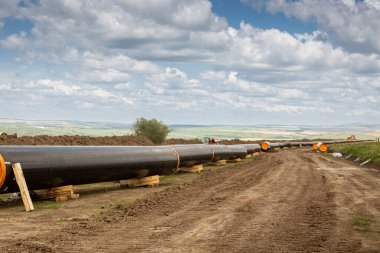 Gaz ve petrol boru hattı inşaatı. Borular kaynaşmış. Büyük boru hattı yapım aşamasında. Bulutlu gökyüzü