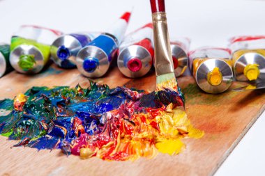 Canlı, yağlı boyalı ve fırçalı bir sanatçı paleti. Resim, hobiler ve sanatsal ifade için sanat malzemeleri ile yaratıcı süreç kavramı.