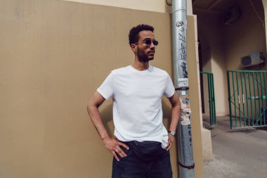 Beyaz, boş tişörtlü ve güneş gözlüklü Afro-Amerikan bir adam. Model.