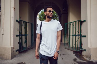 Beyaz, boş tişörtlü ve güneş gözlüklü Afro-Amerikan bir adam. Model.