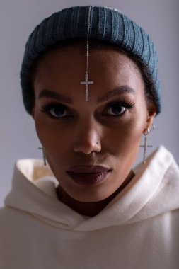 Portrait of an african american woman wearing a hat and with a cross pendant on her forehead.