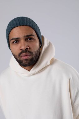African American man in a knitted hat and white oversized hoodie.