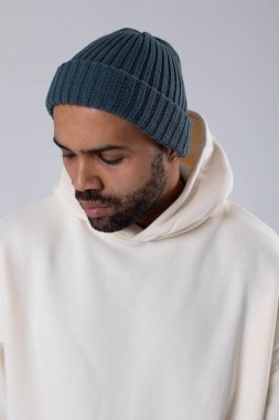 African American man in a knitted hat and white oversized hoodie.