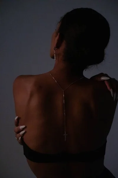 Beautiful back of a young woman. Fashion dark portrait of a woman.