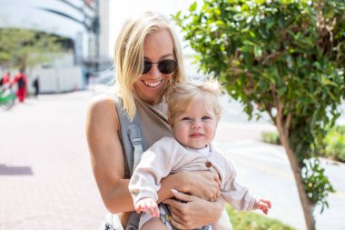 Happy woman with little daughter walking on the street.