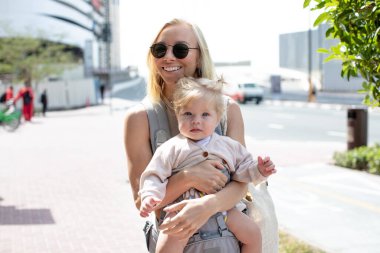 Happy woman with little daughter walking on the street.