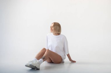 Beyaz arka planda poz veren beyaz tişörtlü güzel bir kız. Yüksek kalite fotoğraf