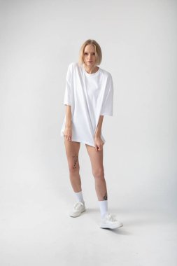 Beyaz arka planda poz veren beyaz tişörtlü güzel bir kız. Yüksek kalite fotoğraf