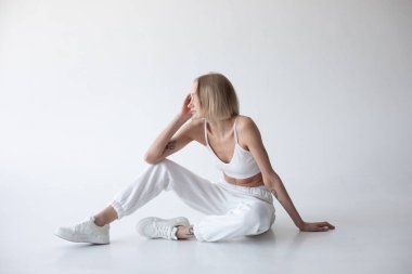 Beyaz bluzlu güzel sarışın kız ve beyaz arka planda poz veren tayt. Yüksek kalite fotoğraf