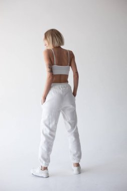 Beyaz bluzlu güzel sarışın kız ve beyaz arka planda poz veren tayt. Yüksek kalite fotoğraf