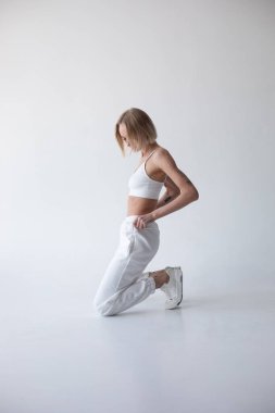 Beyaz bluzlu güzel sarışın kız ve beyaz arka planda poz veren tayt. Yüksek kalite fotoğraf