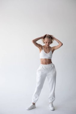 Beyaz bluzlu güzel sarışın kız ve beyaz arka planda poz veren tayt. Yüksek kalite fotoğraf