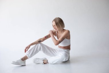 Beyaz bluzlu güzel sarışın kız ve beyaz arka planda poz veren tayt. Yüksek kalite fotoğraf