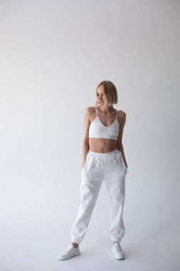 Beyaz bluzlu güzel sarışın kız ve beyaz arka planda poz veren tayt. Yüksek kalite fotoğraf