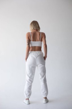 Beyaz bluzlu güzel sarışın kız ve beyaz arka planda poz veren tayt. Yüksek kalite fotoğraf