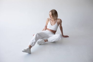 Beyaz bluzlu güzel sarışın kız ve beyaz arka planda poz veren tayt. Yüksek kalite fotoğraf