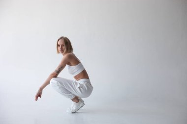 Beyaz bluzlu güzel sarışın kız ve beyaz arka planda poz veren tayt. Yüksek kalite fotoğraf