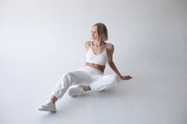 Beyaz bluzlu güzel sarışın kız ve beyaz arka planda poz veren tayt. Yüksek kalite fotoğraf