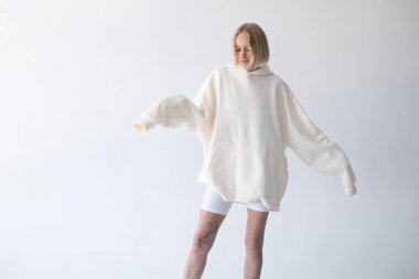 Beyaz kapüşonlu ve beyaz arka planda poz veren güzel sarışın kadın. Yüksek kalite fotoğraf