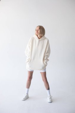 Beyaz kapüşonlu ve beyaz arka planda poz veren güzel sarışın kadın. Yüksek kalite fotoğraf