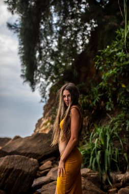 Huzurlu ve sakin bir model kayalık arazide zarafetle poz veriyor, yemyeşil bir güzellikle çevrili.